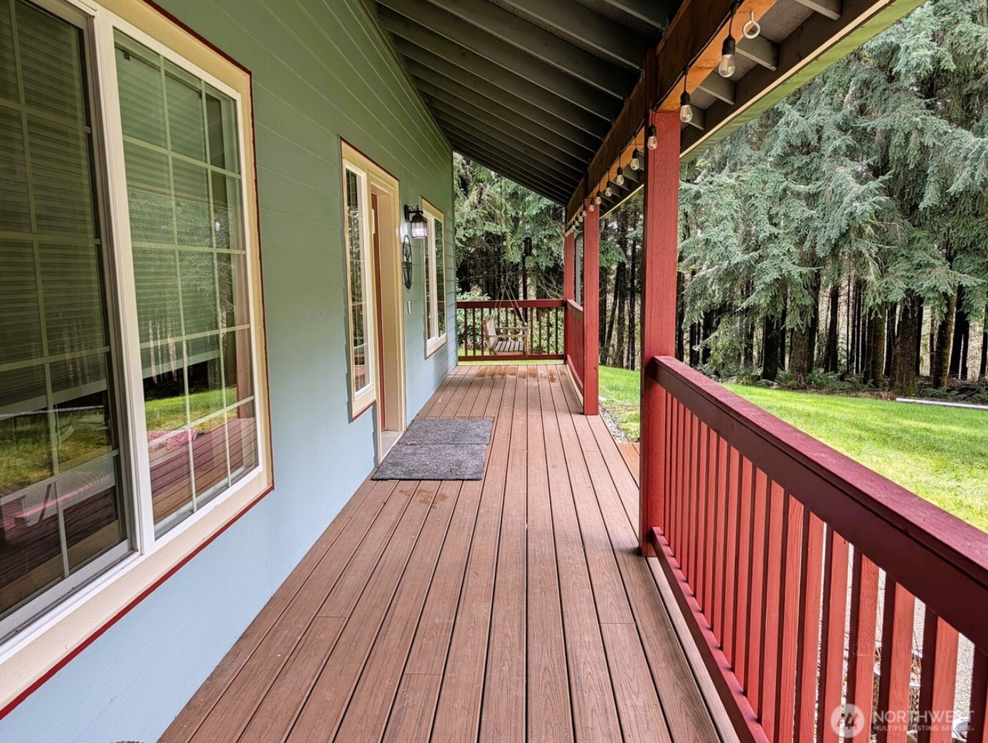 Covered front porch with string lights and wooded surroundings