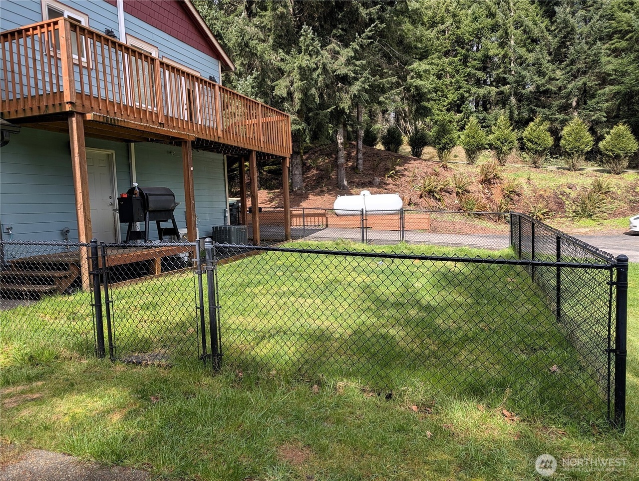 Backyard with fenced pet area, deck and wooded hillside